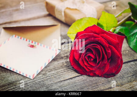 Vintage Happy Valentines Tag Karte. Festliche Komposition mit frischen Rose Blume, Postkarten, Umschläge und Geschenk Box auf dem rustikalen Holztisch. Geschenk für l Stockfoto