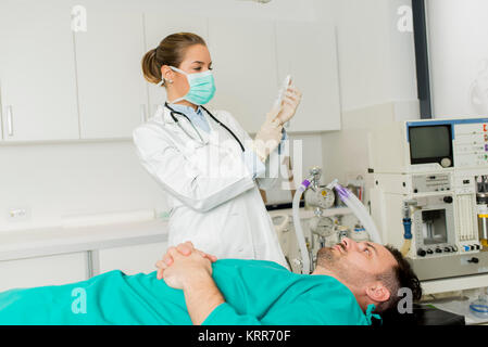 Junge weibliche Arzt Vorbereitung Spritze für männliche Patienten im Krankenhaus Stockfoto