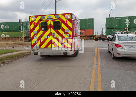 Houston, Texas - ein Houston Feuerwehr EMS Krankenwagen wartet auf eine lengthly Güterzug Quitman Straße in der Nähe von Northside zu löschen. Stockfoto