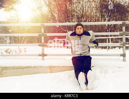 Sport-Mann tut Trizeps Dips am Zaun im winter Stockfoto