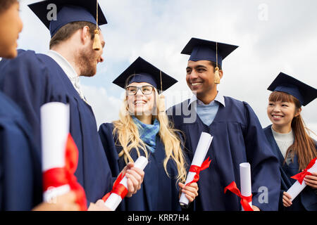 glückliche Schüler in Mörtel-Boards mit Diplomen Stockfoto