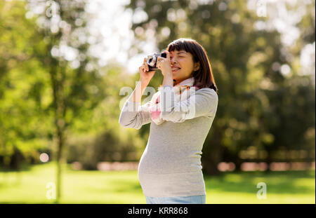 Glücklich schwanger asiatische Frau mit Kamera im Park Stockfoto