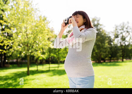 Glücklich schwanger asiatische Frau mit Kamera im Park Stockfoto