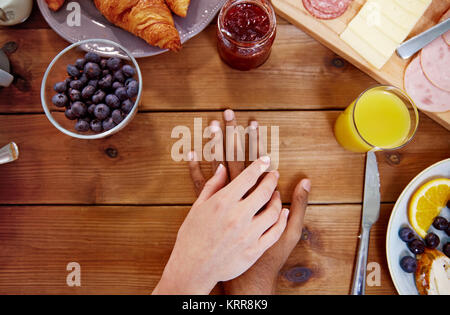 Paar Hände auf dem Tisch voller Essen Stockfoto
