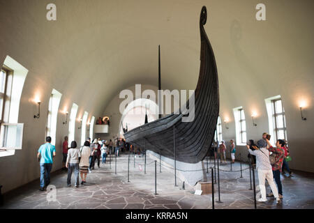 OSLO, Norwegen - Das osebergschiff ist ein außergewöhnlich gut erhaltenen Wikingerschiff, das ist eines der Highlights auf der Viking Ship Museum in Oslo. Es ist nach der Farm, auf der Sie im Jahre 1903 gefunden wurde, benannt. Es wird geglaubt, daß in Norwegen gebaut wurde um 820 AD und hatte im regelmäßigen Einsatz für eine Reihe von Jahren, bevor als schwere Schiff für zwei prominente Frauen in 834 AD verwendet wird. Ihre Körper wurden in der Mitte des Schiffes gelegt, zusammen mit einem reichen Sortiment von Ehrungen. Es ist aus Eiche gebaut und Maßnahmen 22 m lang und 5 m breit. Es könnte gerudert oder gesegelt werden. Von Oslo Wikingerschiff Museu Stockfoto