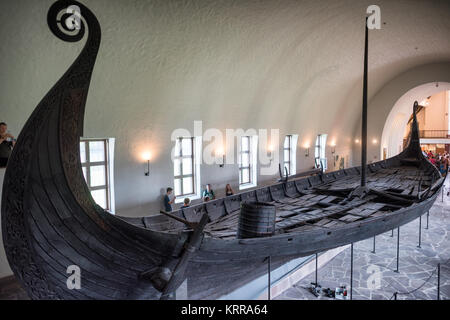 OSLO, Norwegen - Das osebergschiff ist ein außergewöhnlich gut erhaltenen Wikingerschiff, das ist eines der Highlights auf der Viking Ship Museum in Oslo. Es ist nach der Farm, auf der Sie im Jahre 1903 gefunden wurde, benannt. Es wird geglaubt, daß in Norwegen gebaut wurde um 820 AD und hatte im regelmäßigen Einsatz für eine Reihe von Jahren, bevor als schwere Schiff für zwei prominente Frauen in 834 AD verwendet wird. Ihre Körper wurden in der Mitte des Schiffes gelegt, zusammen mit einem reichen Sortiment von Ehrungen. Es ist aus Eiche gebaut und Maßnahmen 22 m lang und 5 m breit. Es könnte gerudert oder gesegelt werden. Von Oslo Wikingerschiff Museu Stockfoto