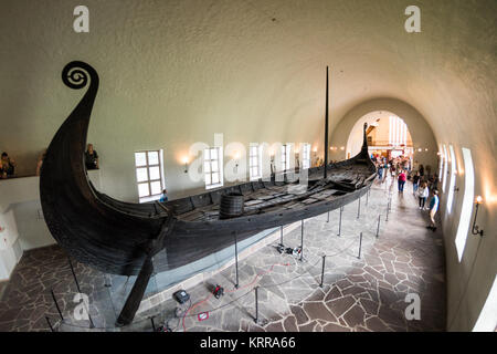 OSLO, Norwegen - Das osebergschiff ist ein außergewöhnlich gut erhaltenen Wikingerschiff, das ist eines der Highlights auf der Viking Ship Museum in Oslo. Es ist nach der Farm, auf der Sie im Jahre 1903 gefunden wurde, benannt. Es wird geglaubt, daß in Norwegen gebaut wurde um 820 AD und hatte im regelmäßigen Einsatz für eine Reihe von Jahren, bevor als schwere Schiff für zwei prominente Frauen in 834 AD verwendet wird. Ihre Körper wurden in der Mitte des Schiffes gelegt, zusammen mit einem reichen Sortiment von Ehrungen. Es ist aus Eiche gebaut und Maßnahmen 22 m lang und 5 m breit. Es könnte gerudert oder gesegelt werden. Von Oslo Wikingerschiff Museu Stockfoto