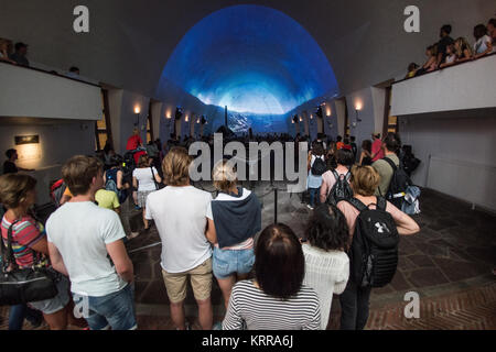 OSLO, Norwegen - Besucher beobachten einer projizierten Film auf der Wikingerzeit in einer der Hallen der Viking Ship Museum in Oslo, Norwegen. Von Oslo Viking Ship Museum beherbergt drei ursprünglichen Wikingerschiffe in verschiedenen Ebenen der Erhaltung sowie einige damit verbundene Artefakte aus der Wikingerzeit. Ihre berühmteste Sehenswürdigkeit ist die Osebgerg Schiff, eine außerordentlich gut erhaltene Beerdigung Schiff zurück zum 9. Jahrhundert zurückgeht. Stockfoto