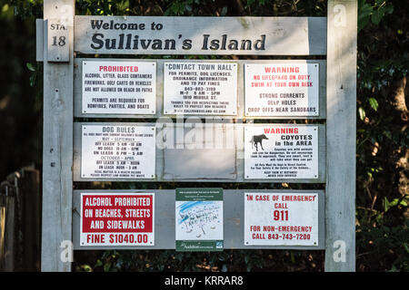 Schild für Strandbestimmungen Sullivan's Island South Carolina // SULLIVAN's ISLAND, South Carolina — Informationsschilder markieren den Eingang zu einem Zugangsweg zum Strand an der Station 18 auf Sullivan's Island, auf dem Besucher wichtige Vorschriften und Sicherheitsinformationen erhalten. Die Schilder beschreiben spezifische Regeln wie Alkoholverbot, Anforderungen an die Hundeleine, die je nach Saison variieren, und Warnungen vor Gefahren beim Schwimmen wie starken Strömungen und tiefen Löchern. Zusätzliche Hinweise weisen Besucher auf die Anwesenheit von Kojoten in der Gegend hin und geben Hinweise zum Schutz nistender Küstenvögel. Die umfassenden Beschilderungen umfassen Stockfoto