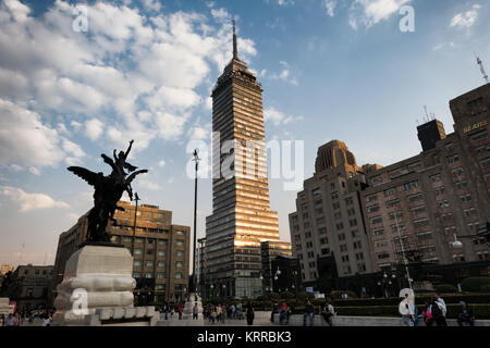 Torre Latinoamericana Pegasus Statue Mexico City // MEXIKO-STADT, Mexiko — eine der vier Pegasus-Statuen des spanischen Bildhauers Agustín Querol steht auf der Plaza de Bellas Artes mit dem Torre Latinoamericana im Hintergrund. Diese dynamischen geflügelten Pferdeskulpturen mit Reitern wurden ursprünglich für die Dachlinie des Palacio de Bellas Artes während der frühen Entwurfsphase unter dem Architekten Adamo Boari in Auftrag gegeben. Die Bronzestatuen wurden in Madrid gegossen und kamen zwischen 1910 und 1911 während der letzten Jahre des Porfirio Díaz-Regimes in Mexiko an. Nach der Fertigstellung des Gebäudes bildet der Pegasus-Sculp Stockfoto