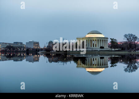 WASHINGTON DC, Vereinigte Staaten – das Jefferson Memorial reflektiert die stillen Gewässer des Tidal Basin im Licht der Dämmerung. Das neoklassizistische Denkmal, das 1943 fertiggestellt wurde, steht als stiller Wächter vor Sonnenaufgang. Die Marmorkuppel und die Säulen des Gedenkwerks erzeugen Spiegelbilder auf der Wasseroberfläche in den ruhigen frühen Morgenstunden. Stockfoto