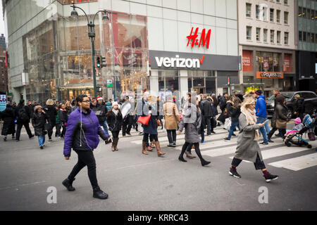 Christmas shopping Fußgänger kreuz Herald Square vor einem Verizon Wireless store und einen H&M-Kaufhaus in New York am Dienstag, 12. Dezember 2017. (© Richard B. Levine) Stockfoto