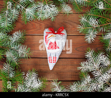 Stoff Weihnachten Herz mit Santa Claus auf einem Holz- und Weihnachtsbaum Hintergrund. Plüschtier Puppe. Karte. Weihnachtsschmuck. Stockfoto