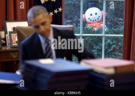 Ein Schneemann Peers durch das Fenster als US-Präsident Barack Obama arbeitet an der entschlossenen Schreibtisch im Oval Office des Weißen Hauses Dezember 16, 2016 in Washington, DC. Stockfoto