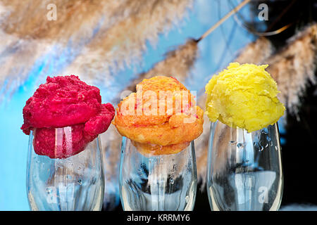 Drei Kugeln Eis auf ein Glas mit einer Landschaft im Hintergrund Stockfoto