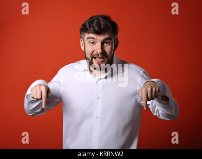 Glücklich, aufgeregt, bärtigen business Mann im weißen Hemd, mit dem Finger auf rotem Hintergrund. Closeup Portrait Stockfoto