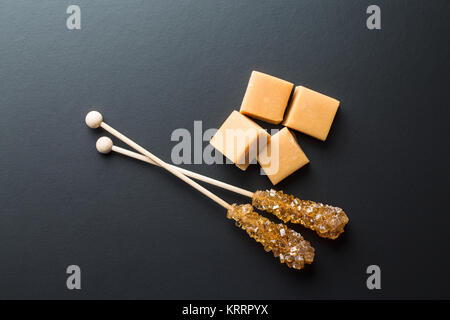 Brauner Zucker Kristalle auf Stick und Karamell Bonbons. Stockfoto