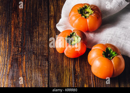 Drei Persimonen auf Tisch Stockfoto