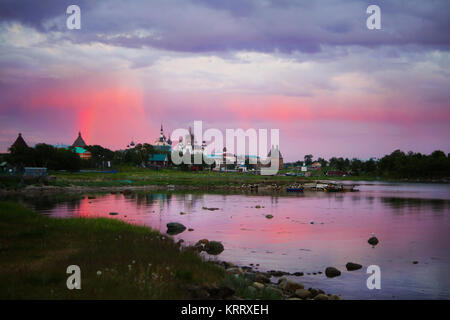 Solovetsky Kloster bei Sonnenuntergang in den Regenbogenfarben, die auf der Oberfläche des Meeres in der Bucht reflektiert wird. Karelien, Russland Stockfoto