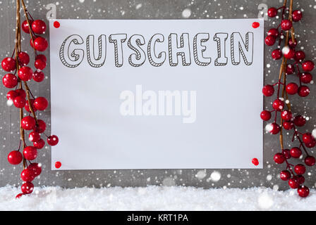 Etikett mit deutschem Text Gutschein Gutschein bedeutet. Rot Weihnachten Dekoration auf Schnee. Urban und modernen Zement Wand als Hintergrund mit Schneeflocken. Stockfoto