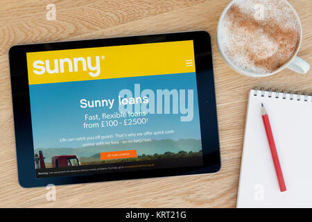 Die Sonnige Website auf einem iPad Tablet Gerät, das auf einem Tisch liegt neben einem Notizblock und Bleistift und eine Tasse Kaffee (nur redaktionell) Stockfoto