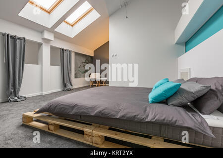 Einfache Dachgeschoss Schlafzimmer mit DIY-Palette Bett und Fenster in der Decke Stockfoto