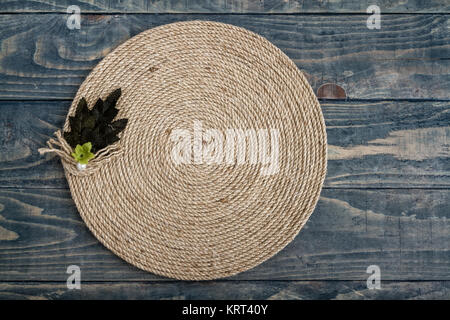 Handgefertigt tisch Matte aus Jute Seil in einer Spiralform auf Blau Holz- Hintergrund verdreht Stockfoto