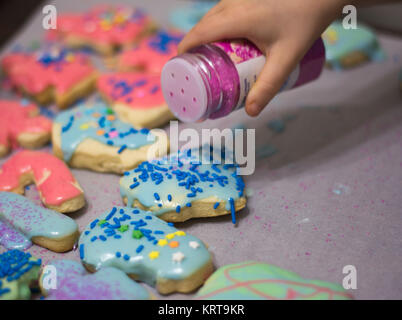 Weihnachtsplätzchen layed heraus auf Tabelle junge Hand sie verzieren Stockfoto