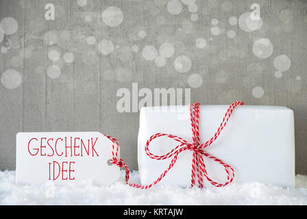 Etikett mit deutschem Text Geschenk Idee bedeutet Geschenk Idee. Ein Weihnachtsgeschenk oder auf Schnee. Zement Wand als Hintergrund mit Bokeh. Moderne und den urbanen Stil. Stockfoto