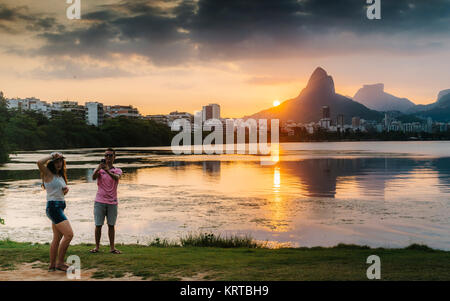 Rio de Janeiro, Brasilien - 19. Dez 2017: Junges Paar Bilder mit Blick auf den Morro Dois Irmaoes von Lagoa Rodrigo de Freitas in Rio de Janeiro bei Sonnenuntergang gesehen, d Stockfoto