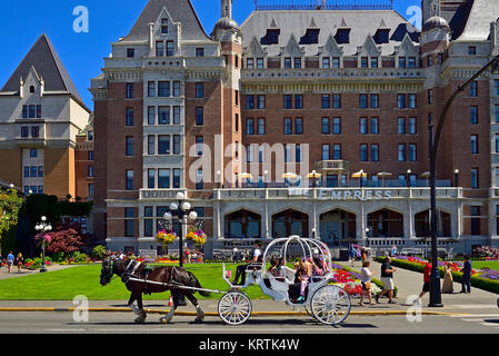 Ein weißes Pferd Kutsche entlang der Hauptstraße fahren mit einer Last von touristischen Fluggäste vor dem Empress Hotel in der Stadt Victoria o Stockfoto