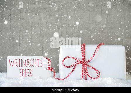 Etikett mit deutschem Text bedeutet Weihnachtsfeier Weihnachtsfeier. Ein Weihnachtsgeschenk auf Schnee. Zement Wand als Hintergrund mit Schneeflocken. Moderne und den urbanen Stil. Stockfoto