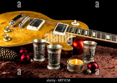 E-Gitarre verziert mit Becher und Kerze zu Weihnachten Stockfoto