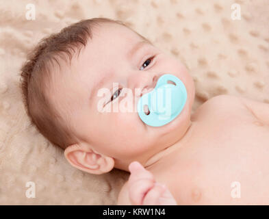 Cute Baby lächelnd mit blau Schnuller Stockfoto