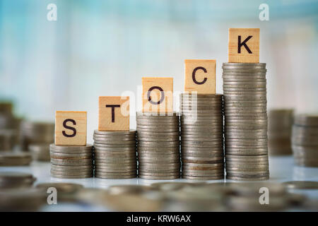 Stzck von Münzen mit Holz- Scrabble Buchstaben Stockfoto