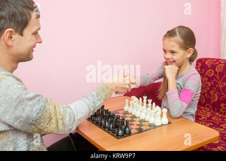 Vater und Tochter begrüßt einander Hände, eine Partie Schach spielen Stockfoto