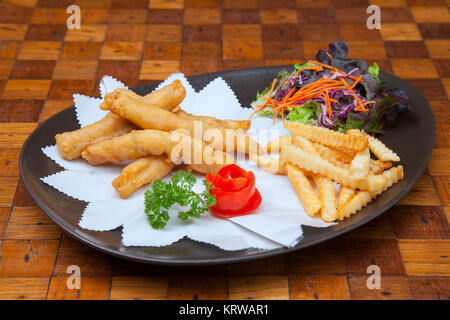 Köstlich knusprige Fisch und Chips - gebratener Kabeljau Pommes frites Zitronenscheiben Remoulade und Erbsenpüree auf Platte auf Papier auf Holz- Tabelle Vorderansicht von ab Stockfoto