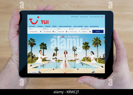 Ein Mann schaut auf die TUI-Website auf seinem iPad tablet device, Schuß gegen einen hölzernen Tisch top Hintergrund (nur redaktionelle Nutzung) Stockfoto