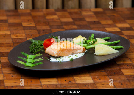 Atlantischer Lachs mit Rucola, mit Gemüse auf einer schwarzen Platte eingerichtet. Stockfoto