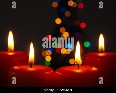 Vier brennende Advent Kerzen mit unscharfen Lichter Hintergrund eines Weihnachtsbaumes Stockfoto