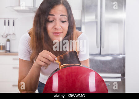 Frau nehmen Toast Aus dem Toaster verbrannt Stockfoto