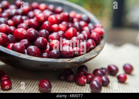 Frische Preiselbeeren im rustikalen Holzmöbeln Schüssel auf sackleinen Hintergrund ein Stockfoto