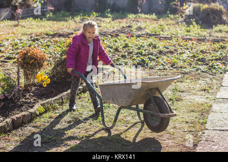 Gerne kleine Mädchen sitzen in Schubkarren Stockfoto