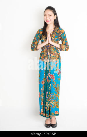 Südostasiatische Frau in Batik Kleid Gruß Stockfoto