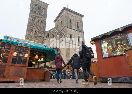 Osnabrück, Deutschland. 20 Dez, 2017. Menschen gehen in zwischen den Ständen des Weihnachtsmarktes in Osnabrück, Deutschland, 20. Dezember 2017. Die Kathedrale St. Peter im Hintergrund gesehen werden. Credit: Friso Gentsch/dpa/Alamy leben Nachrichten Stockfoto