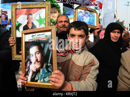 (171221) - aleppo (Syrien), Dez. 21, 2017 (Xinhua) -- Menschen halten Plakate der Syrischen 'Märtyrer' während der Feier der Befreiung von Aleppo auf dem Saadallah al-Jabiri Square in Aleppo Stadt, nördliches Syrien, am Dez. 21, 2017. Der jubiläumsfeier enthalten auch eine militärische Parade und den Familien der 'Märtyrer' propagiert, die ihr Leben im Krieg verloren haben, die Plakate mit den Fotos ihrer getöteten Söhne und Brüder. Schlacht im letzten Jahr von Aleppo war ein Wendepunkt im Zuge von Aktionen, die in der syrischen Krise, wegen der strategischen Bedeutung der Stadt, whi Stockfoto