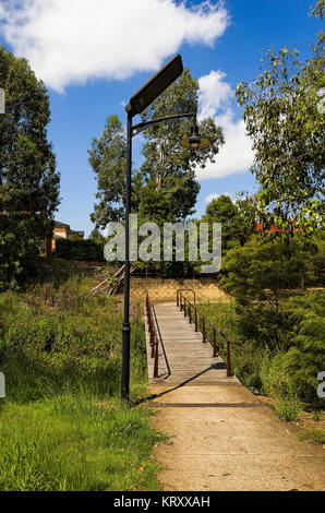 Eine Solar Lampe über einen Fußweg in der Nähe von einer hölzernen Fußgängerbrücke in Sydney, Australien. Stockfoto