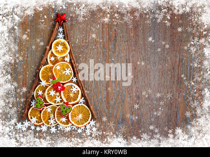 Weihnachten Baum der orange Scheiben, Schneeflocken und Weihnachtsschmuck auf einem schneebedeckten Holz- Hintergrund. Weihnachten, Winter, neues Jahr Konzept Stockfoto