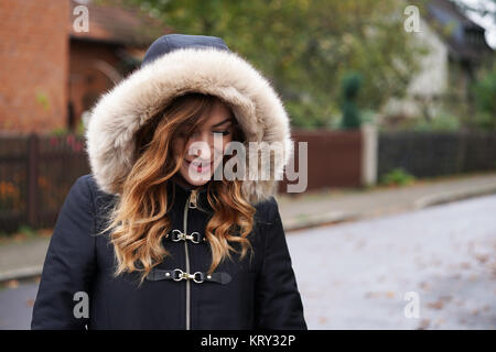 Junge Frau trägt mit Kapuze Wintermantel spielen Coy Stockfoto