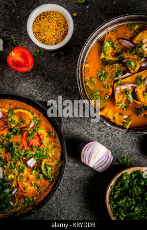 Indische Küche Rezepte, Masala Omelett Omelett mit und indische Masala Ei Curry, mit frischem Gemüse - Tomate, hot chili Pfeffer, Petersilie dunklen Stein bac Stockfoto